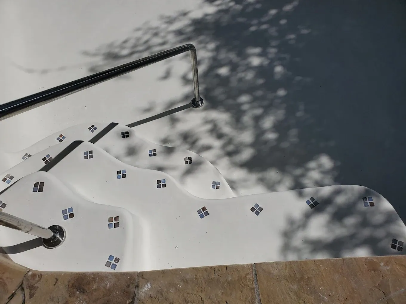 Two men are working on the floor of a swimming pool.