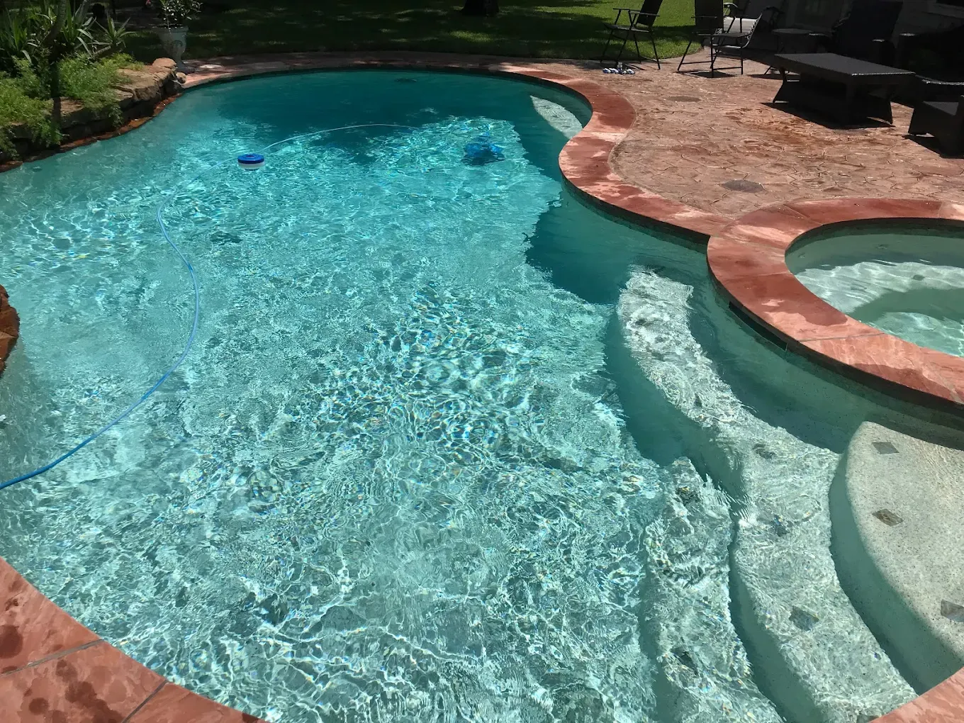 A man is cleaning a swimming pool with a vacuum cleaner.