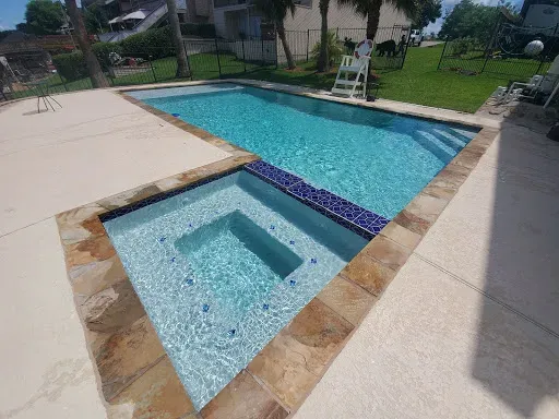 A large swimming pool with a fence around it and trees in the background.