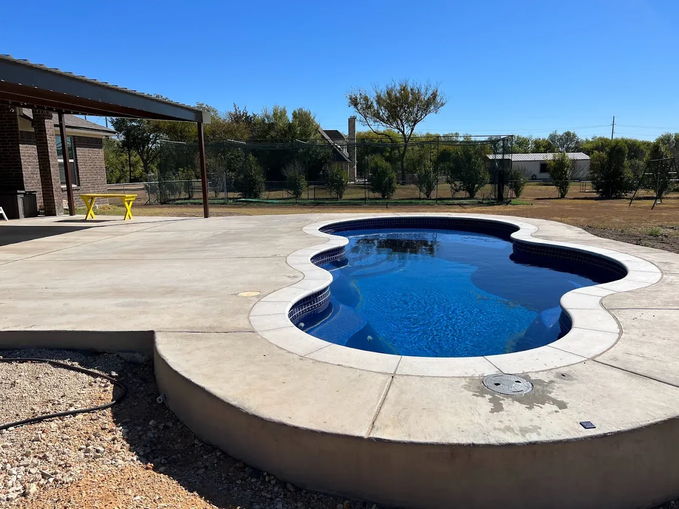 A swimming pool with a cover on it and a fence in the background.