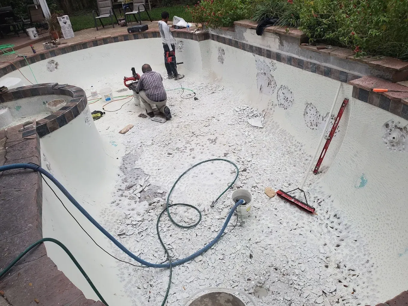 A man is kneeling in the middle of a swimming pool.