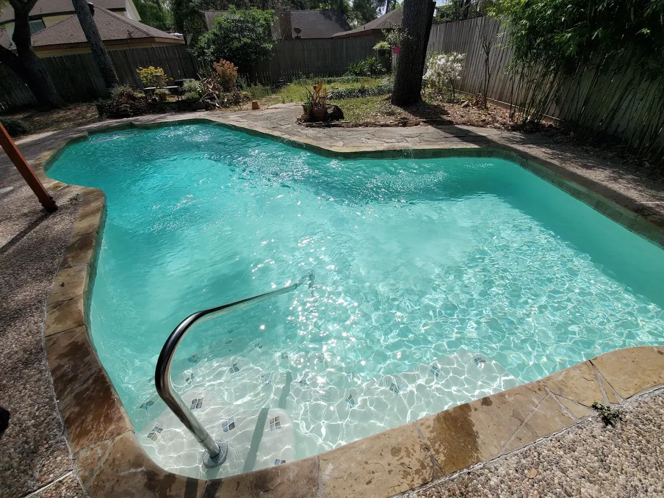 A large swimming pool in a backyard with a fence in the background.