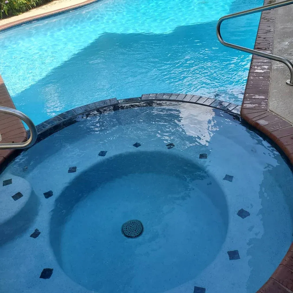 A man in a red shirt is working on a swimming pool.