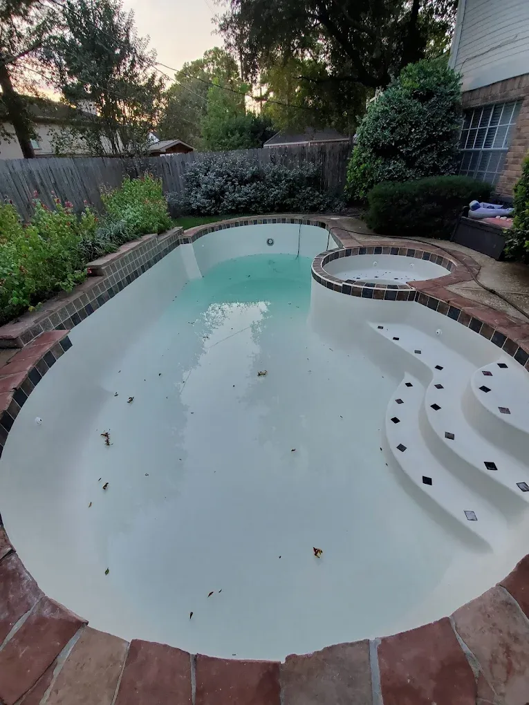 There is a large swimming pool in the backyard of a house.