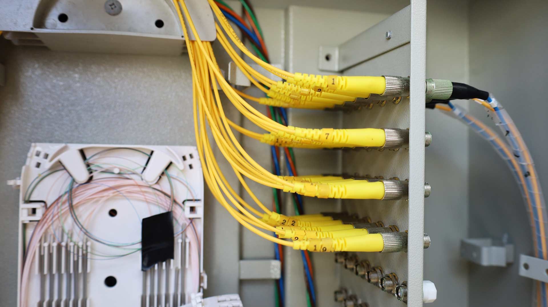 Open utility box with yellow fiber optic cables and connectors.