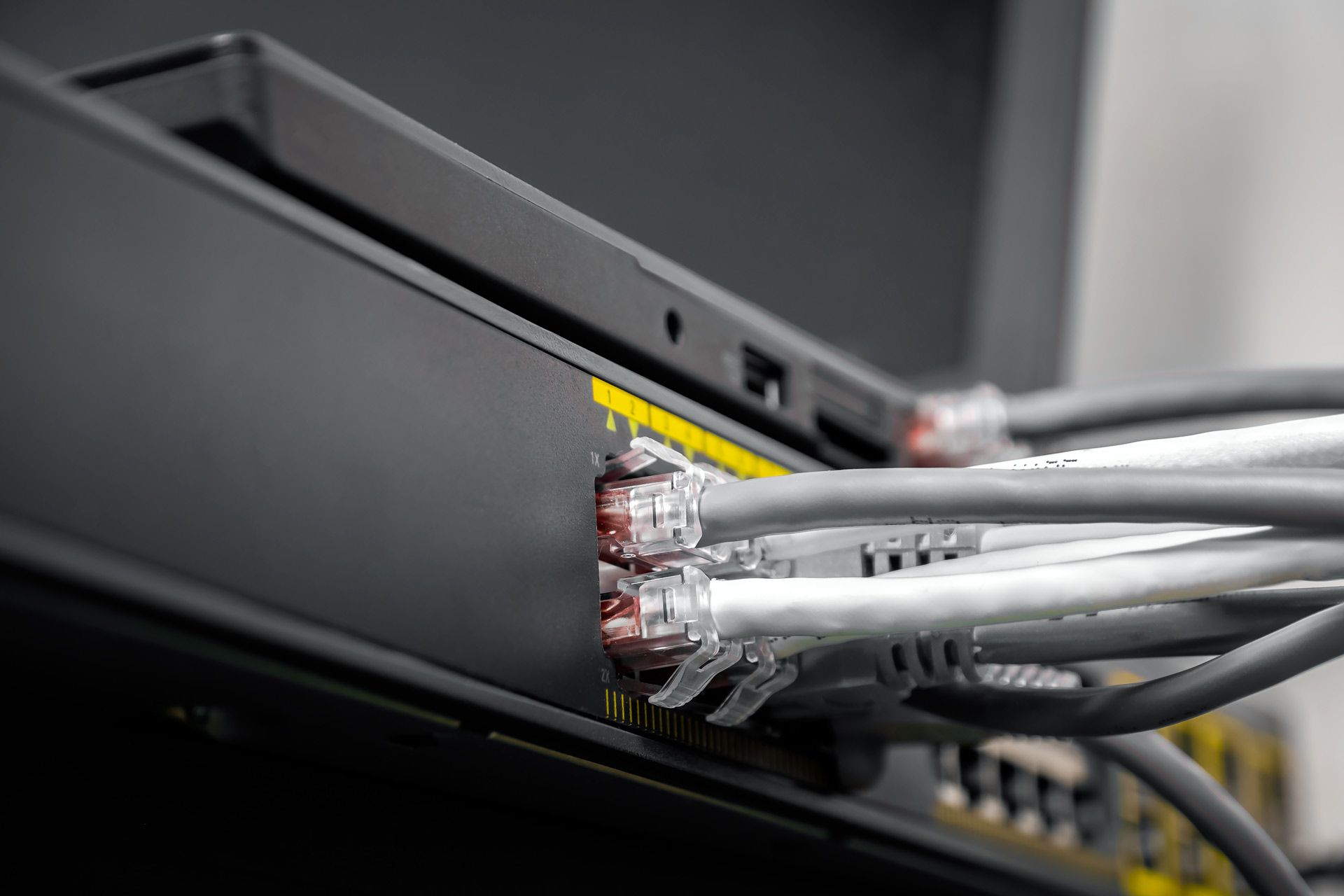 Black network switch with gray Ethernet cables plugged into its ports.