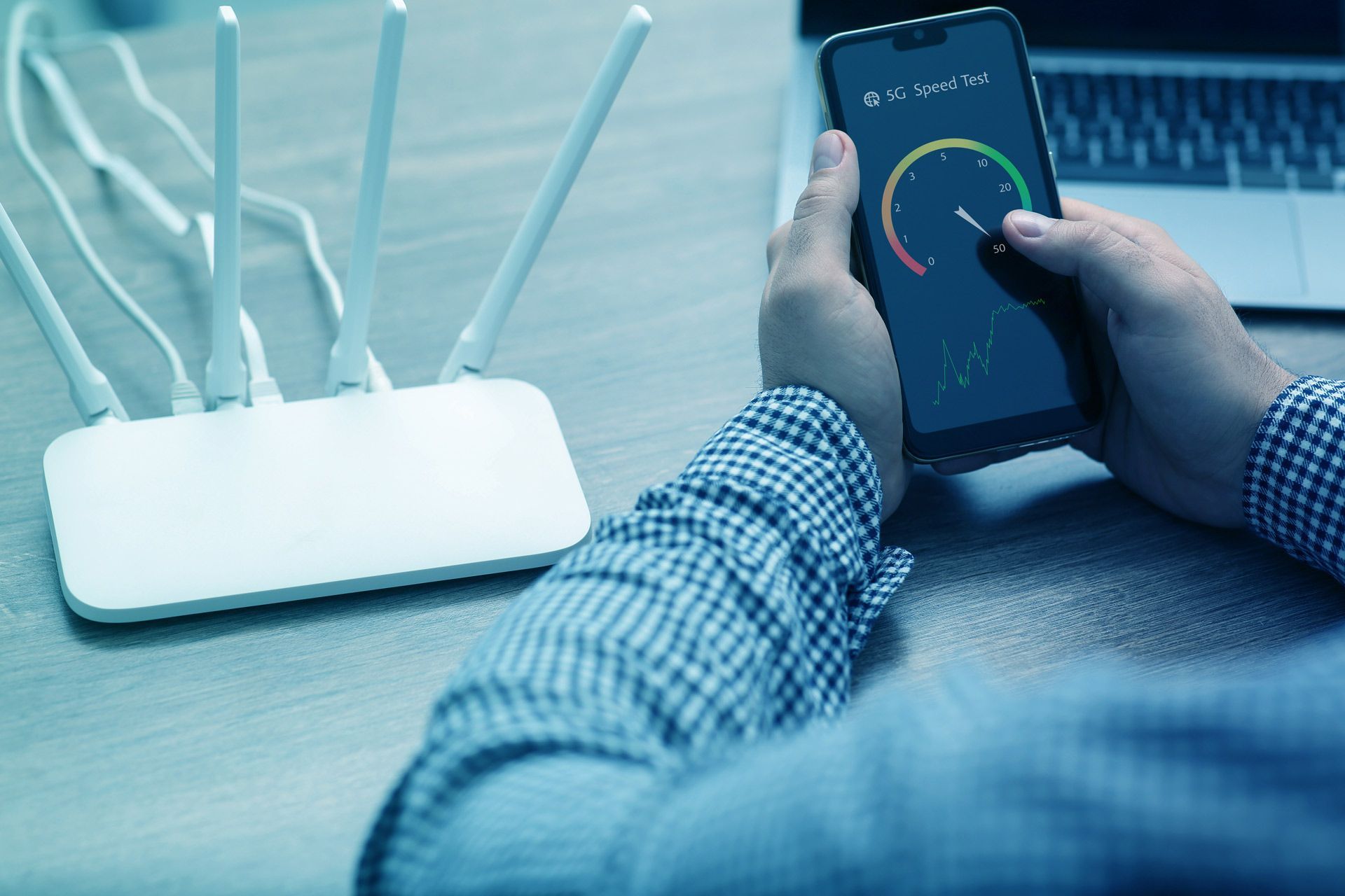 Person holding phone, testing WiFi speed, near a router with four antennas.