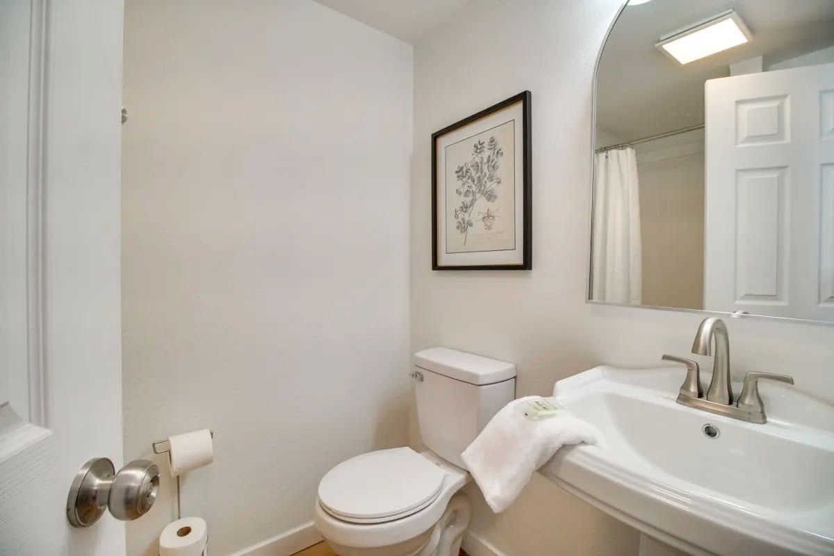 A bathroom with a toilet , sink and mirror.
