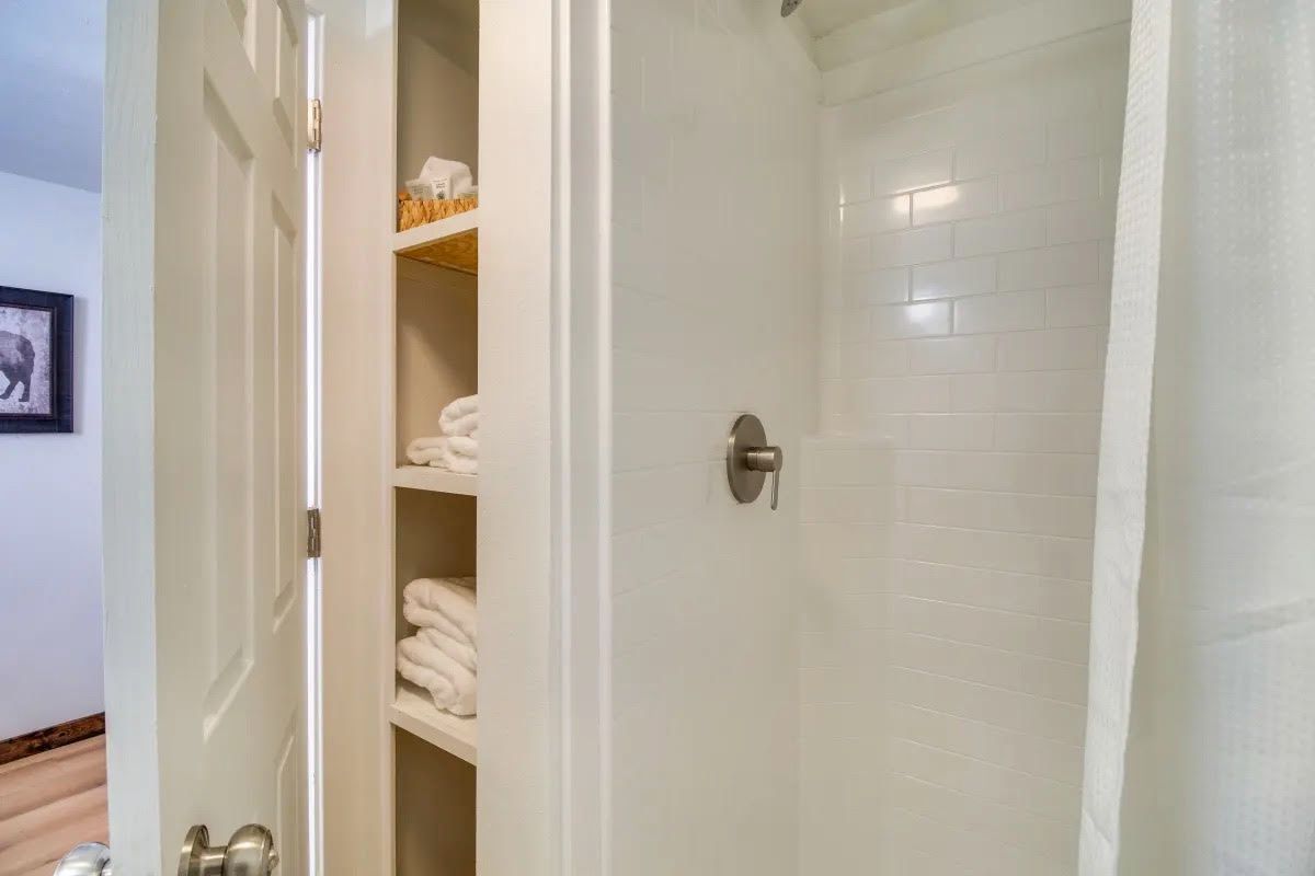 A bathroom with a shower and a closet filled with towels.