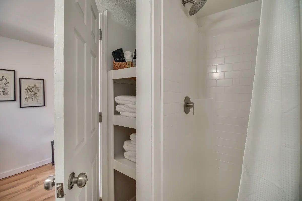 A bathroom with a shower and a closet filled with towels.