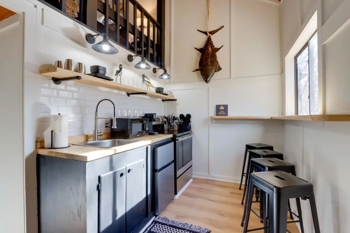 A kitchen with a sink , stove , and stools.