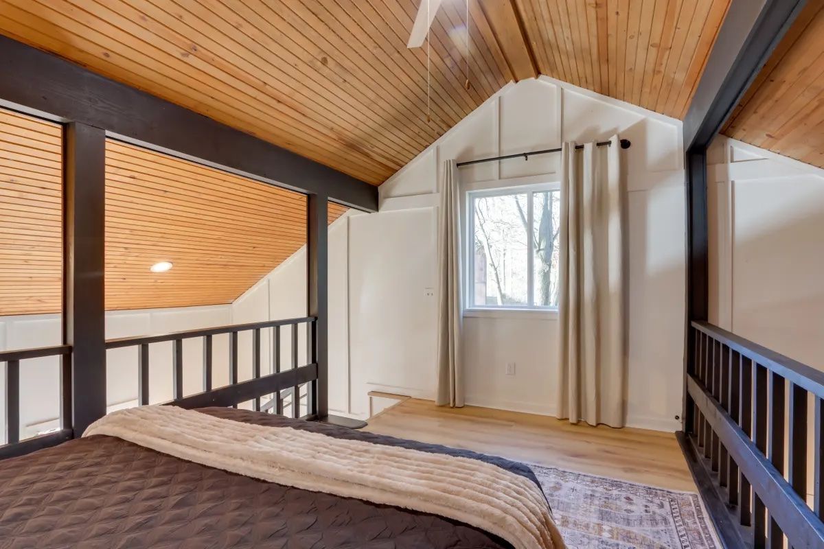 A bedroom with a bed and a balcony with a ceiling fan.
