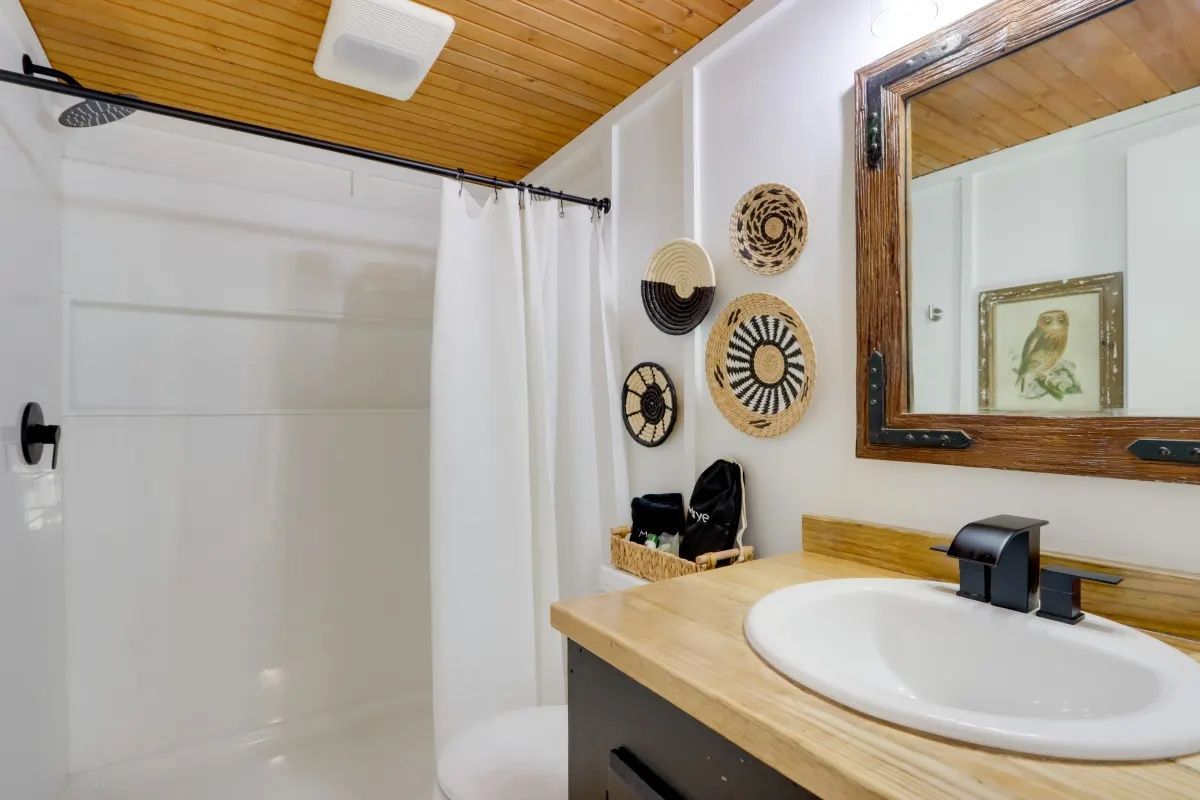 A bathroom with a sink , mirror and shower.