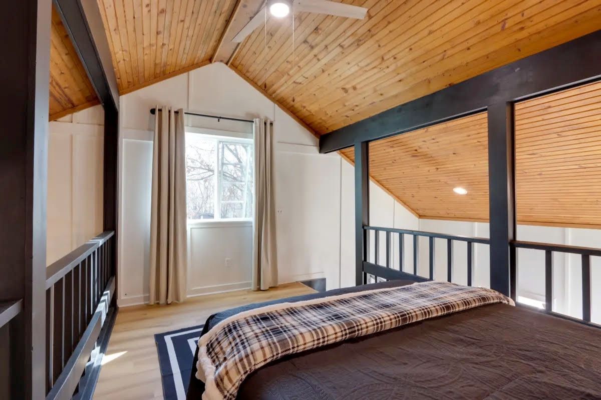 A bedroom with a wooden ceiling and a bed.
