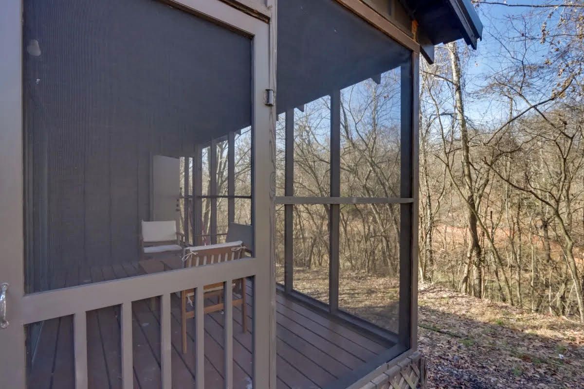 A screened in porch with a view of the woods.