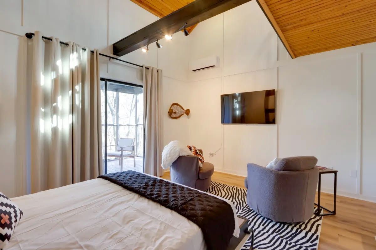 A bedroom with a bed , chairs , and a television.