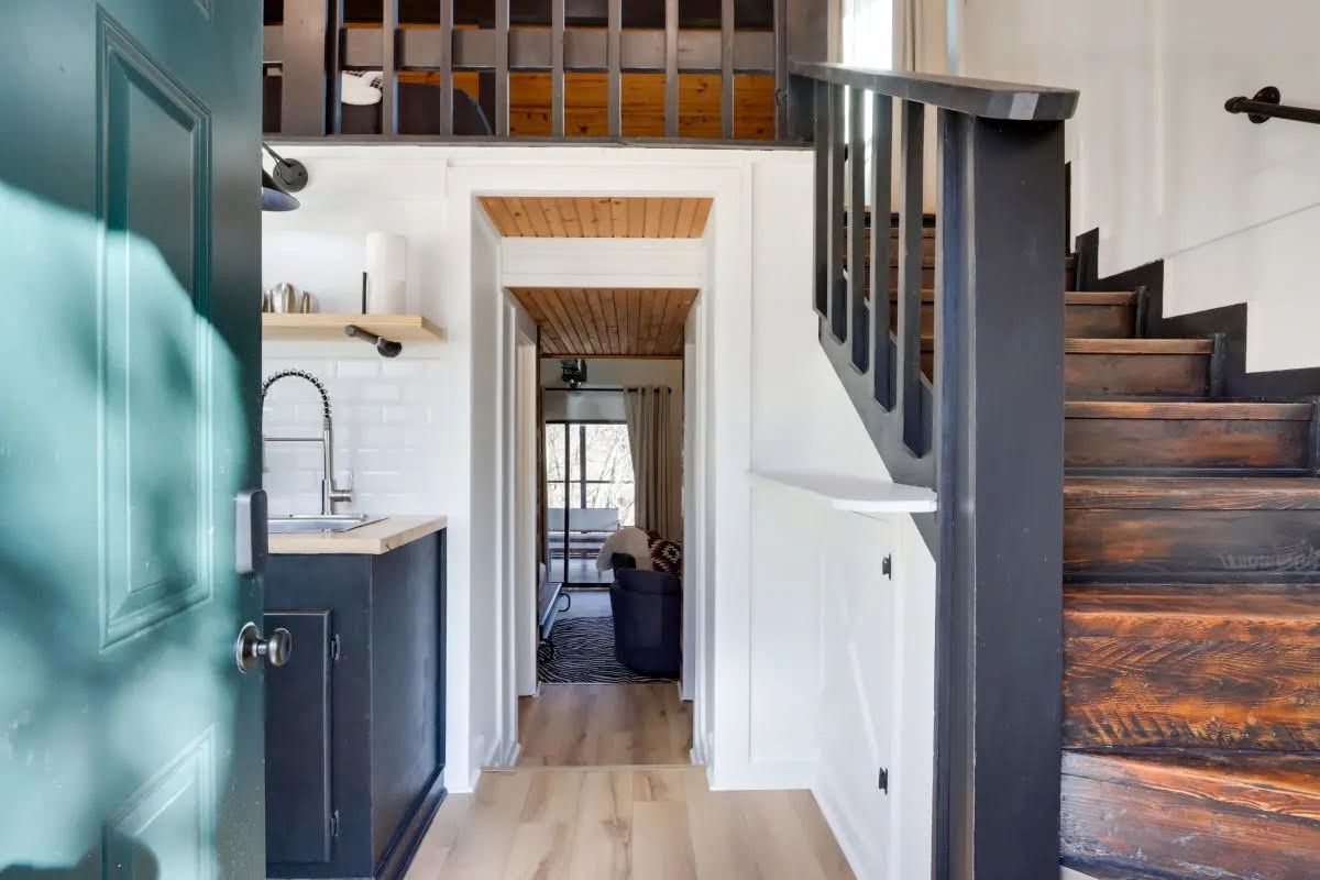 A kitchen with a sink and stairs leading up to the second floor.
