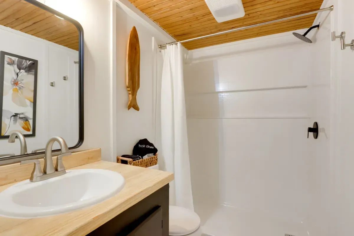 A bathroom with a sink , toilet , shower and mirror.