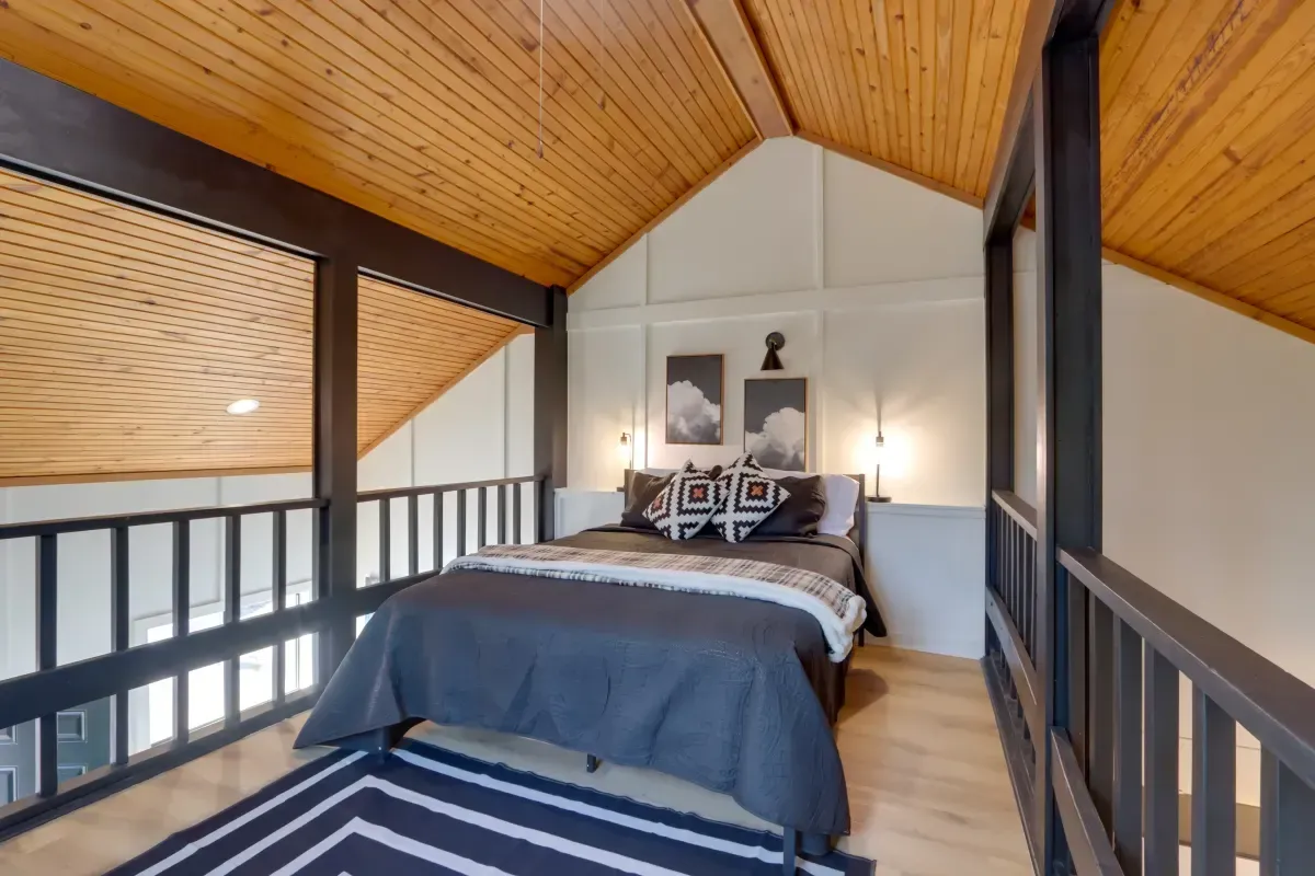 A bedroom with a bed and a rug on the floor.