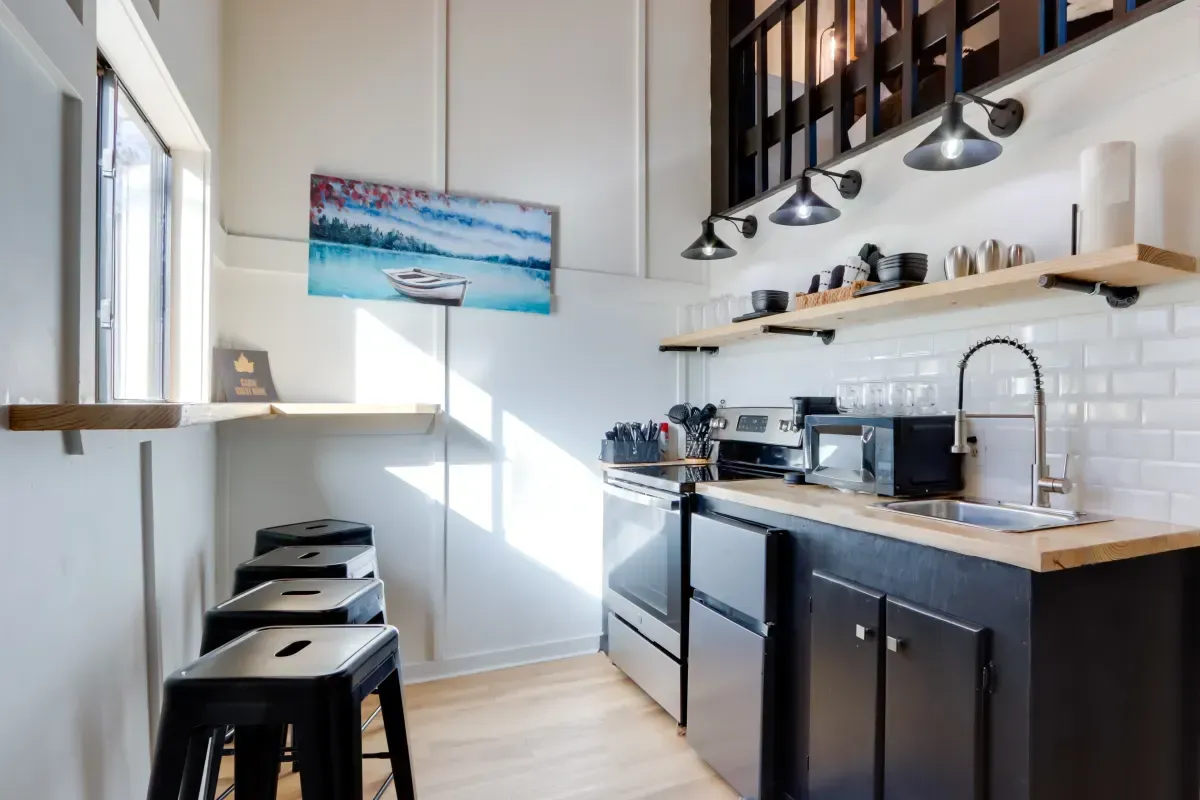A kitchen with a sink , stove , microwave and stools.