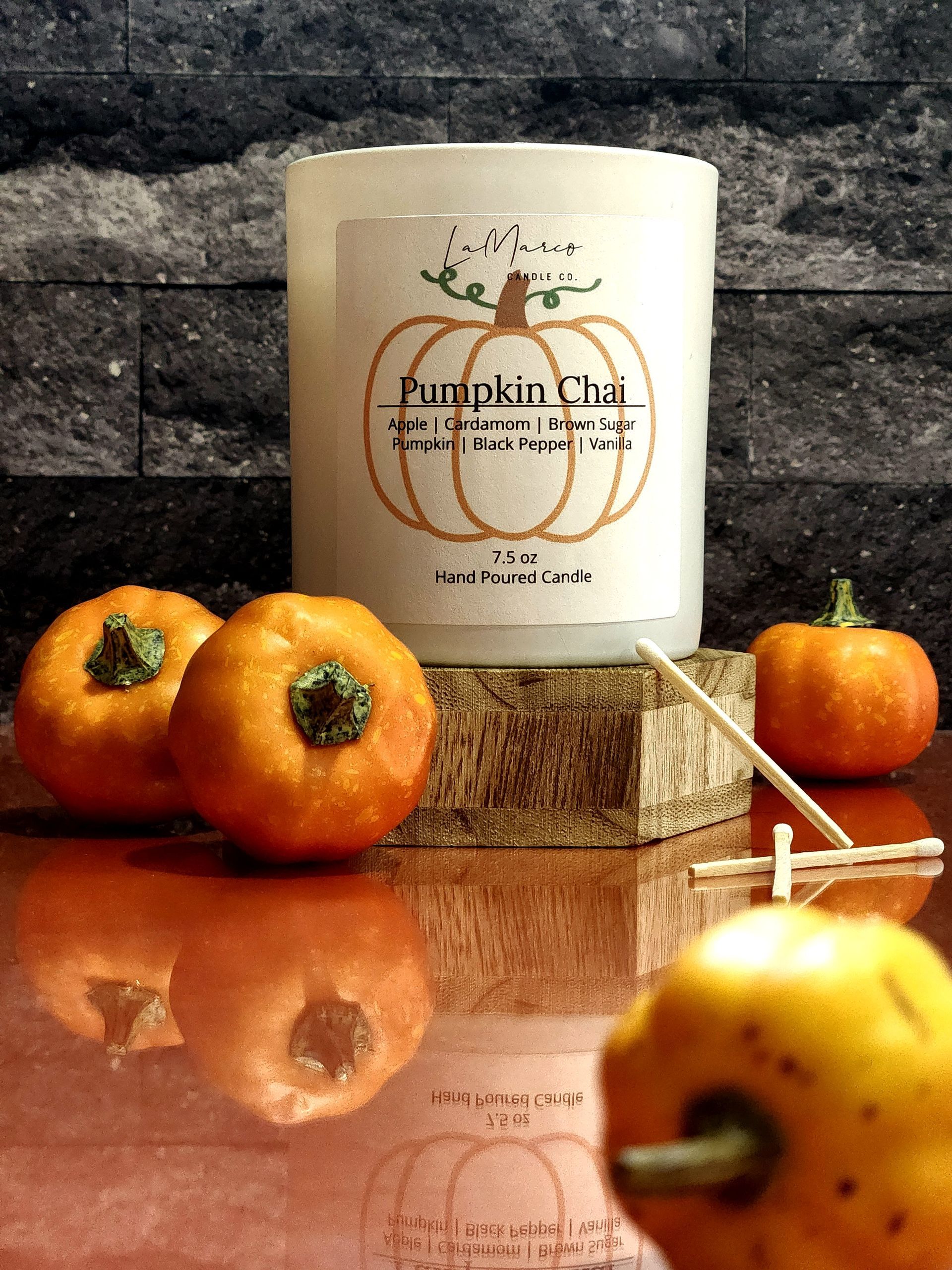 White and orange pumpkin-shaped ceramic containers with gold accents on a reflective orange surface, autumn-themed.