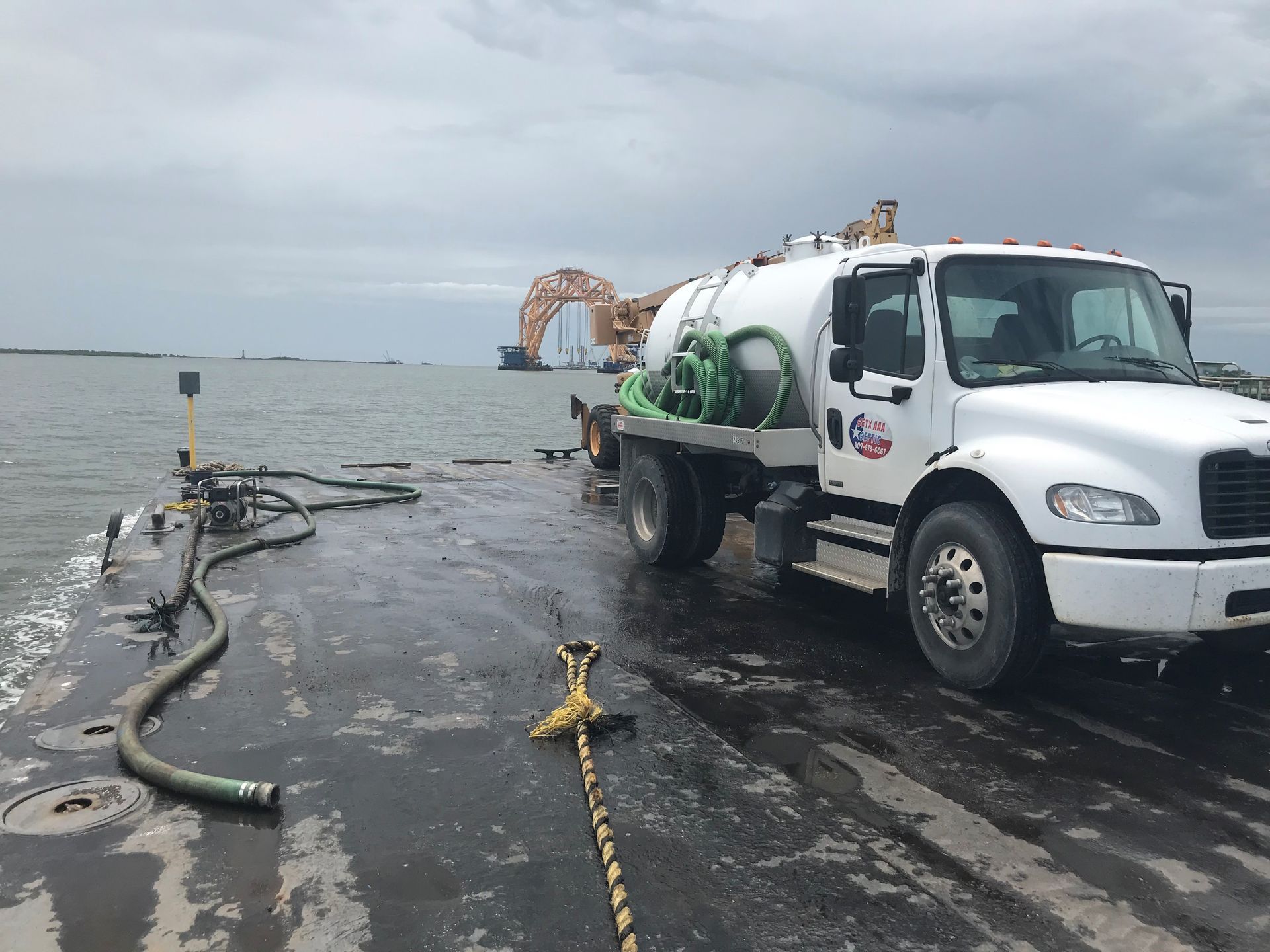 White utility truck beside flooded road with hoses; an orange lifebuoy ring in the water under cloudy skies