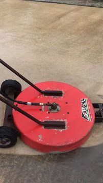 Red circular floor scrubber with black handle on concrete floor