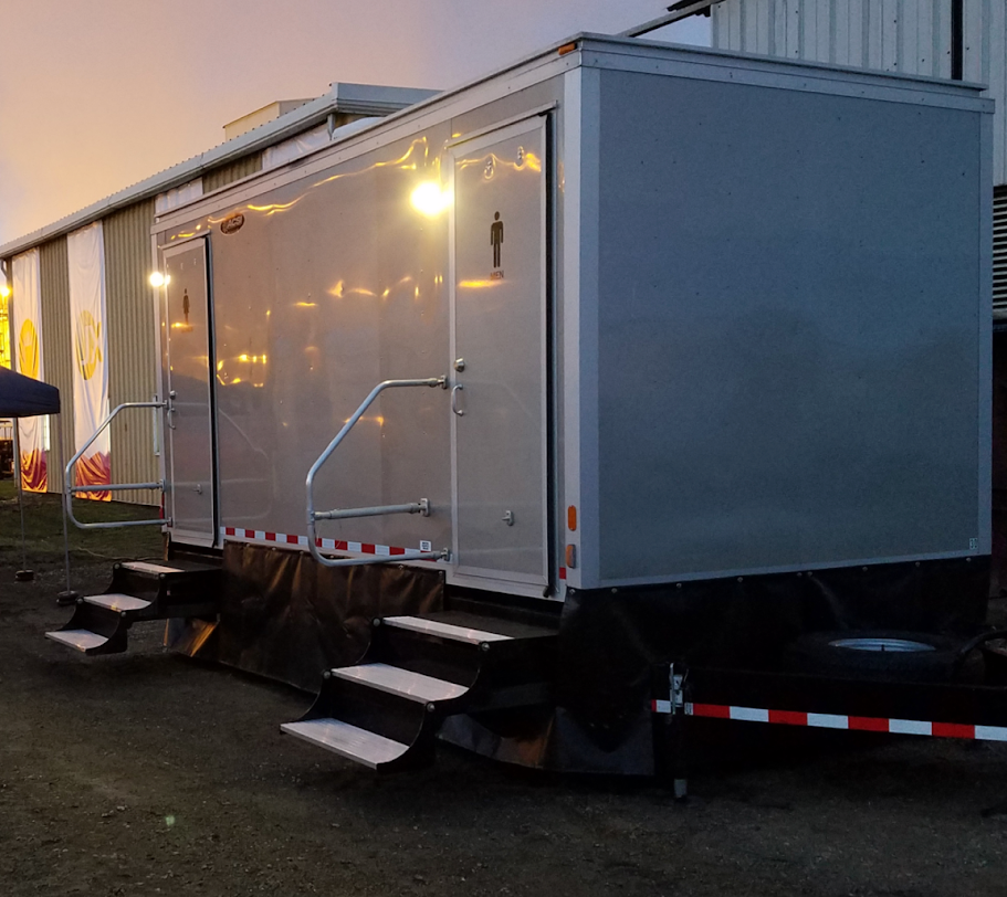 White mobile trailer with steps parked outdoors at dusk