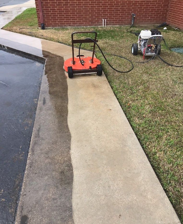 Orange pressure washer cleaning a concrete sidewalk beside a brick building, with a generator nearby