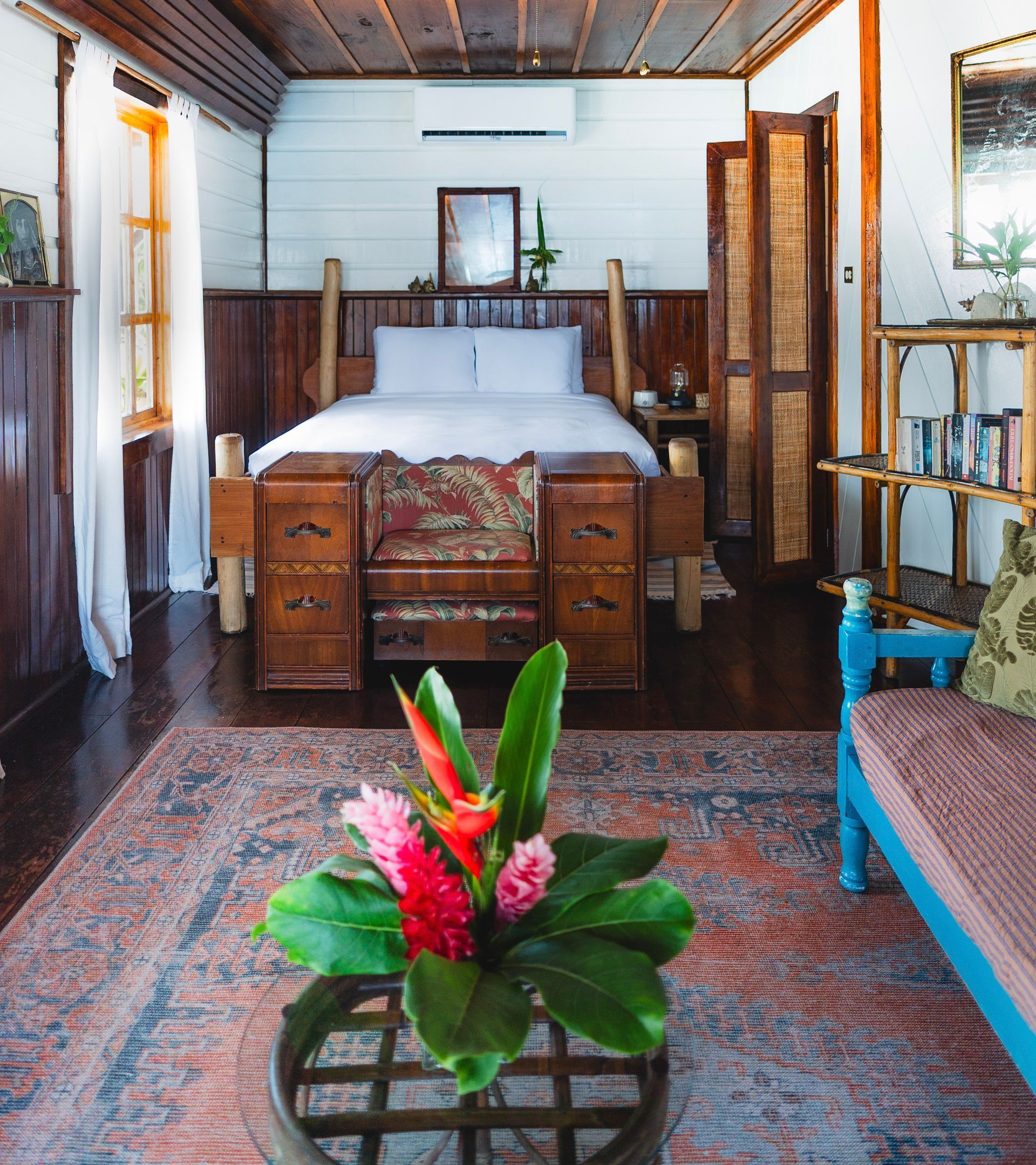 A living room with a bed and a table with flowers on it