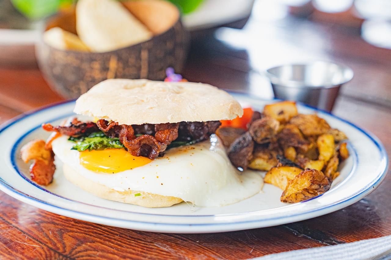 A plate of food with eggs , bacon and potatoes on a table.