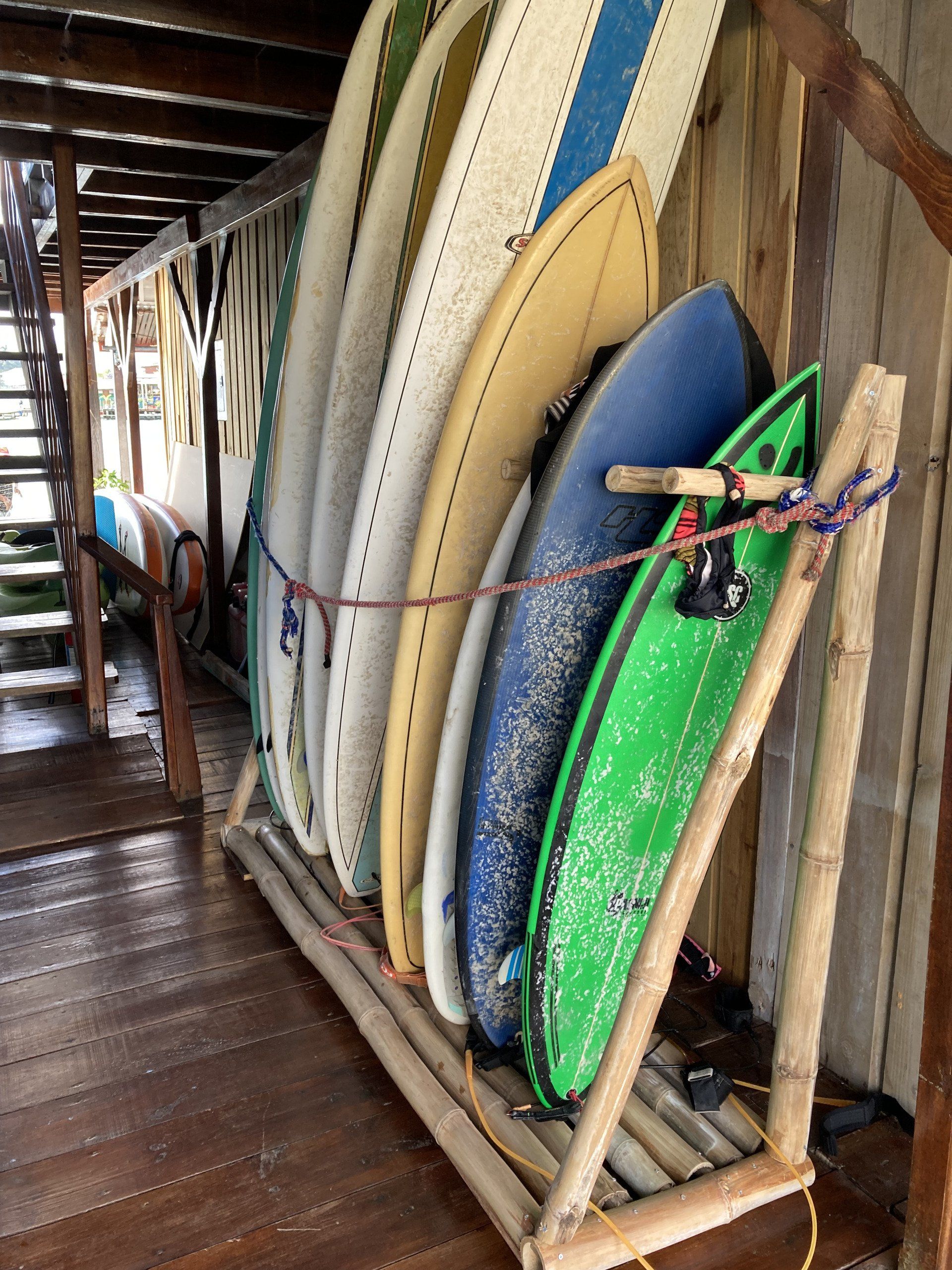 A bunch of surfboards are stacked on a wooden rack