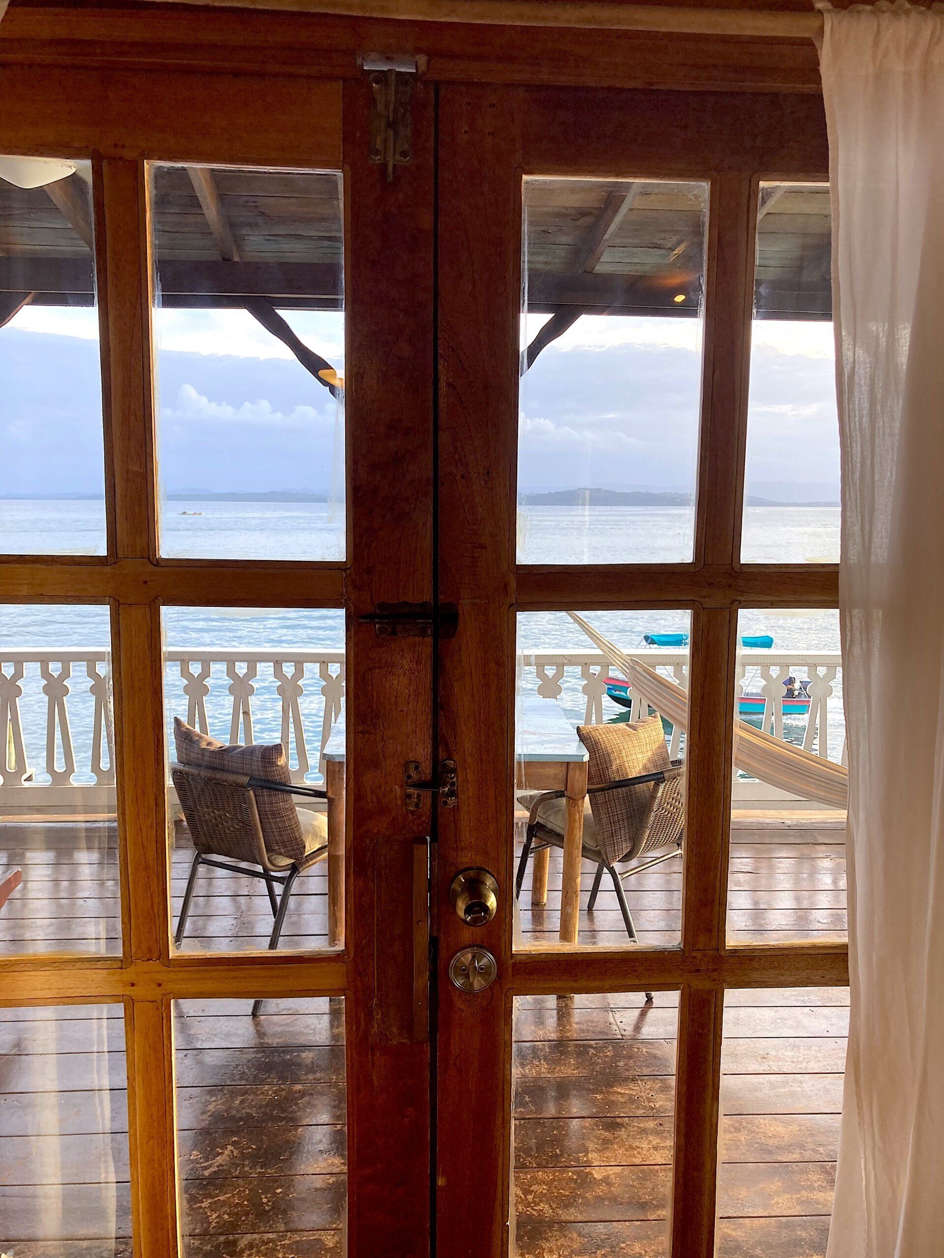 A wooden door with a view of a balcony overlooking the ocean