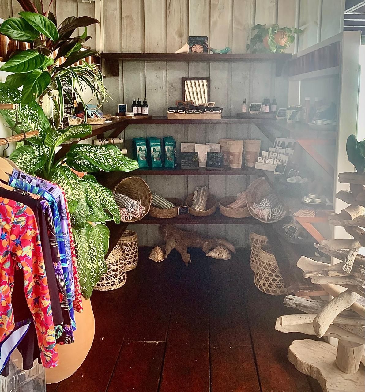 Bohemian-style shop display with patterned bags, colorful textiles, plants, and carved wood decor