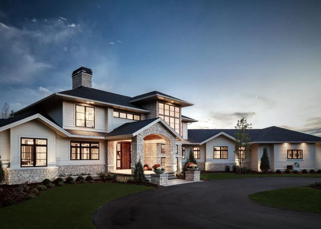 Luxurious modern home with stone accents, dark roof, and manicured lawn.