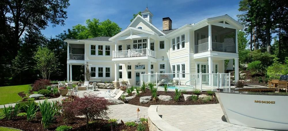 White house with patio, pool, and boat on a sunny day.