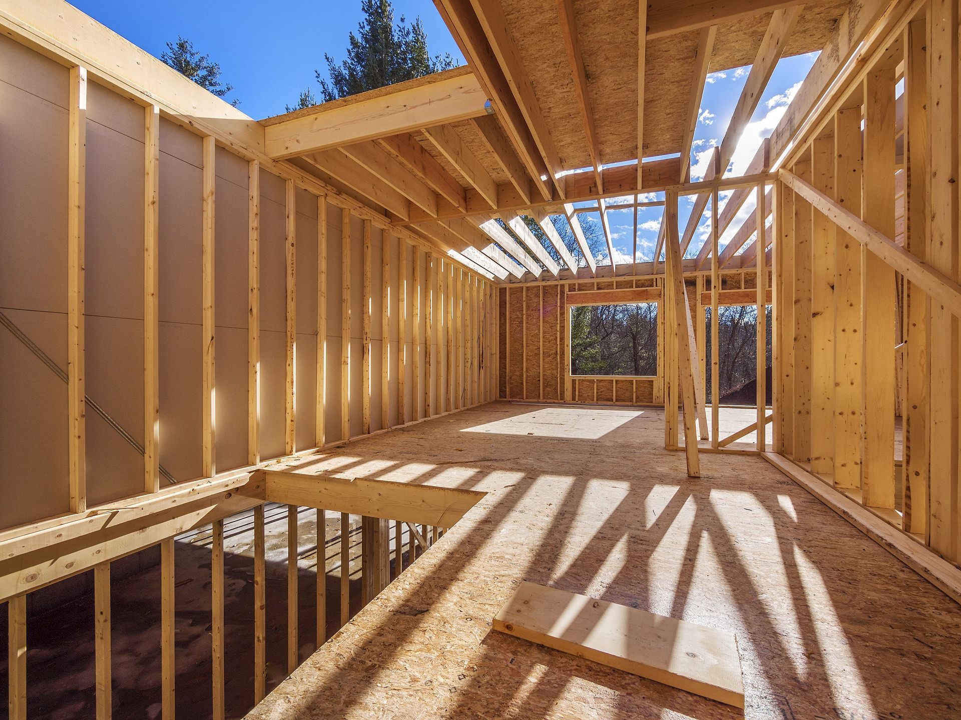 Interior view of a building under construction, showing wooden framing for walls, floor, and ceiling.