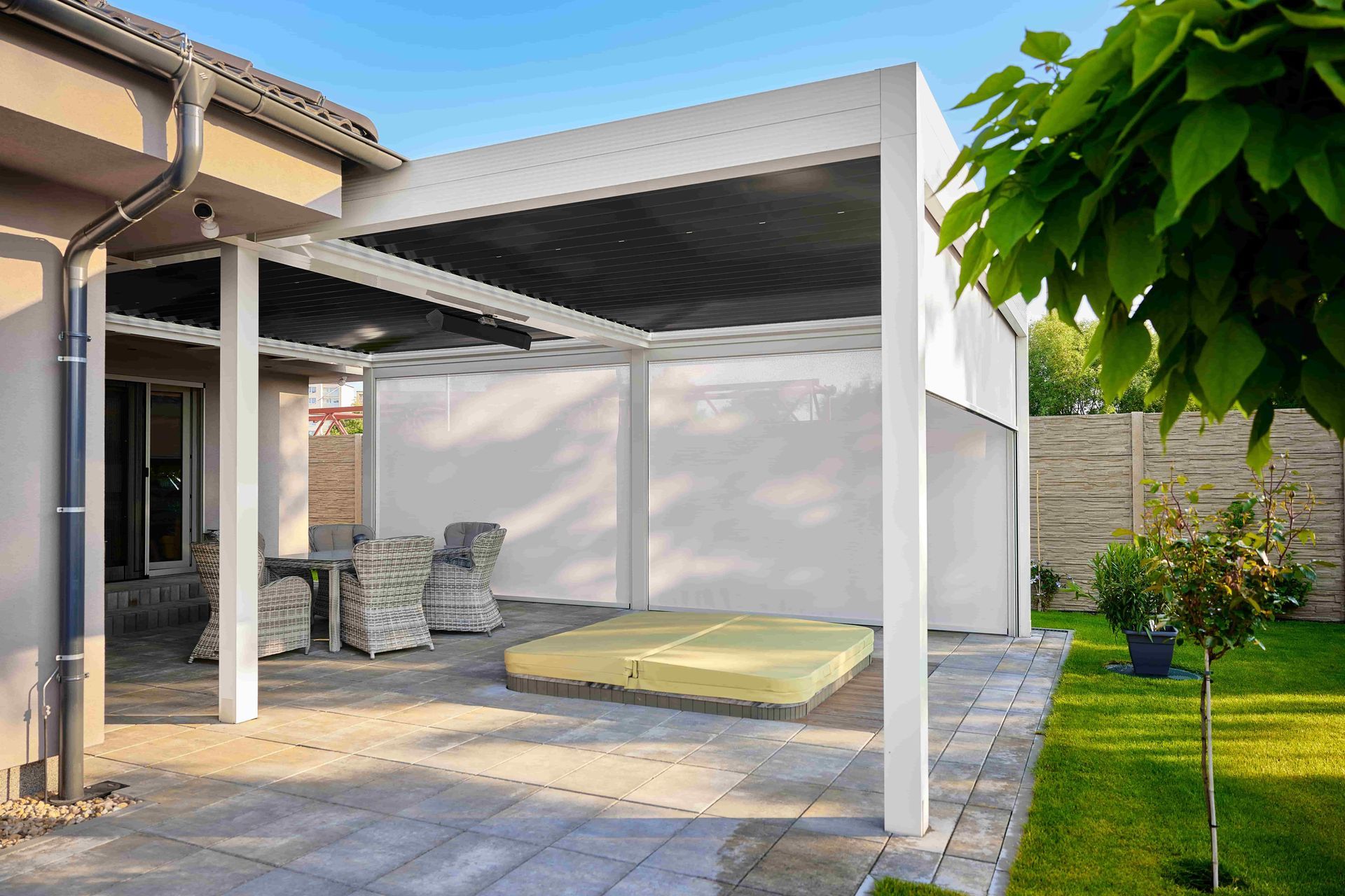 Outdoor patio with white pergola, seating area, hot tub, and lush green lawn.