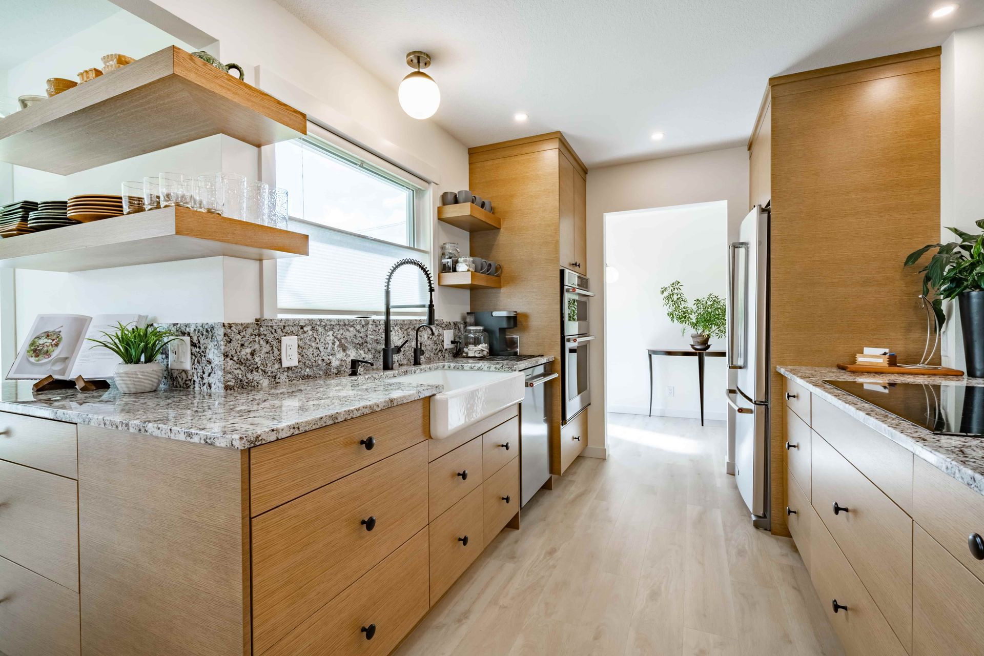 Modern kitchen with light wood cabinets, granite countertops, and stainless steel appliances.