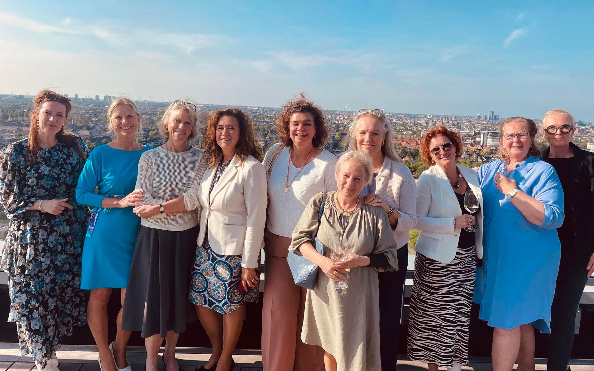 Een groep lachende dales, Las Hotellas, staat buiten met de stad op de achtergrond, op een zonnige dag.