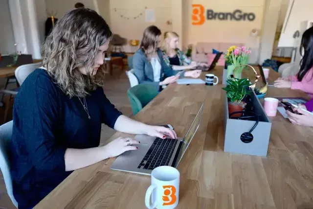A group of people are sitting at a table using laptops.