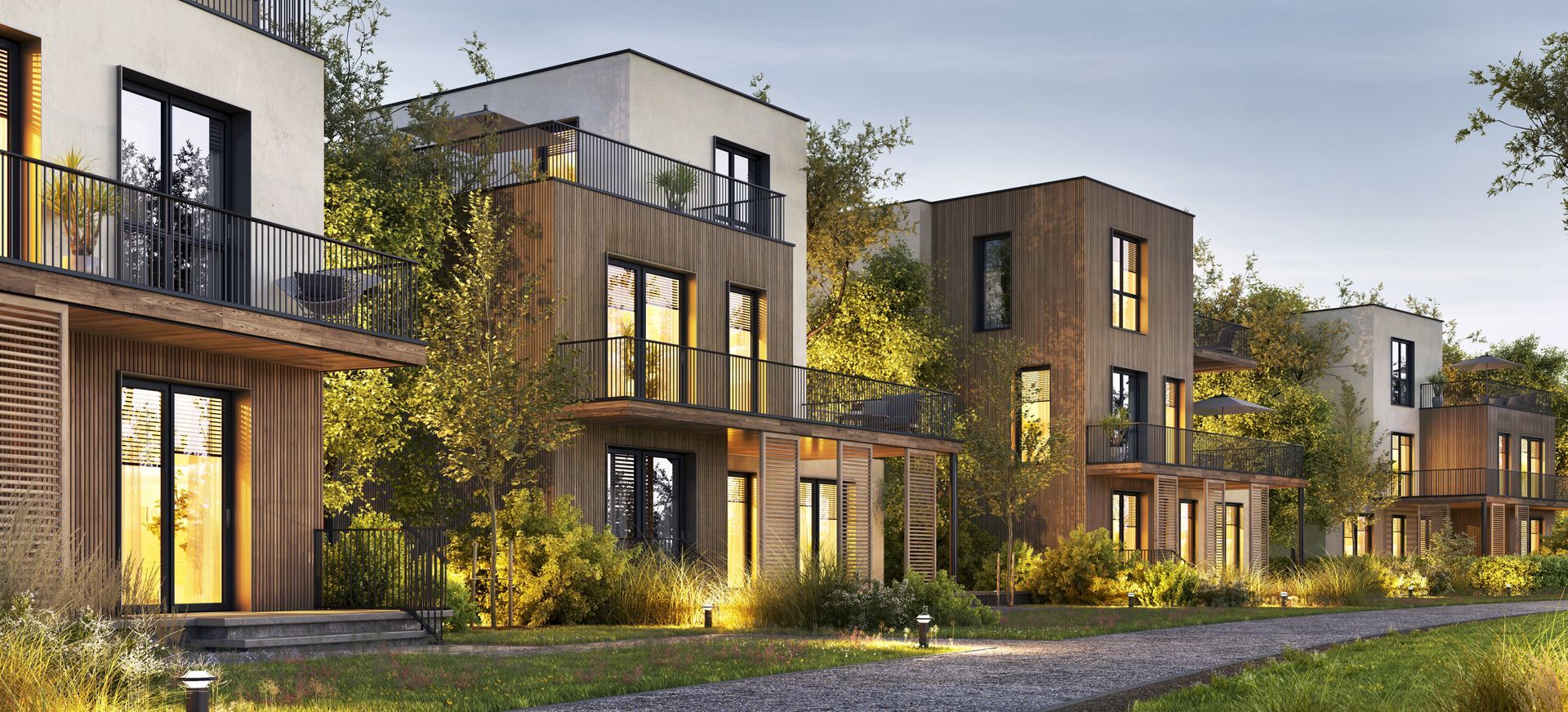 Modern apartment buildings with balconies and warm exterior lighting at dusk