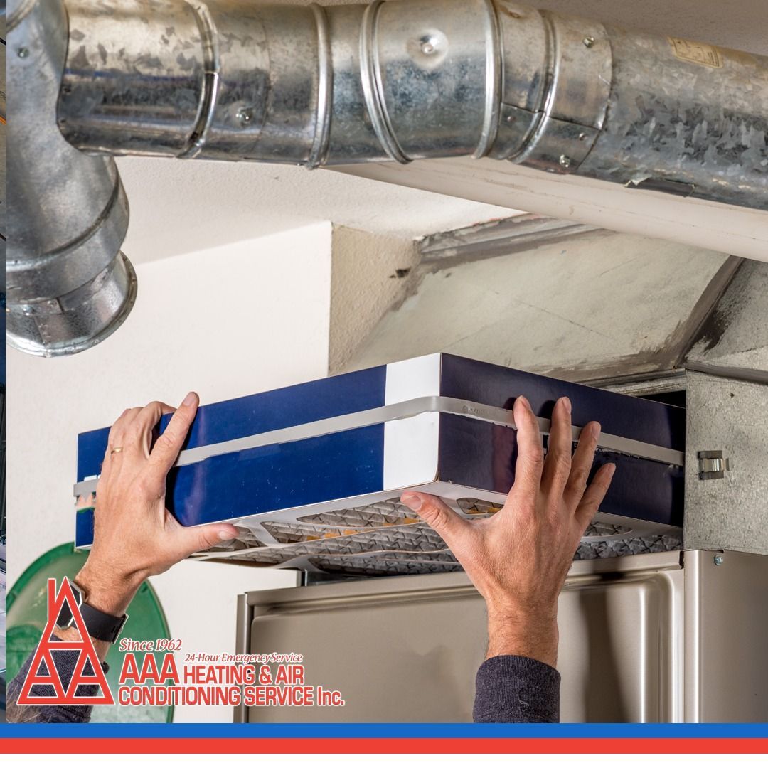Hands replacing a blue and white air filter in an HVAC system, near ducts.