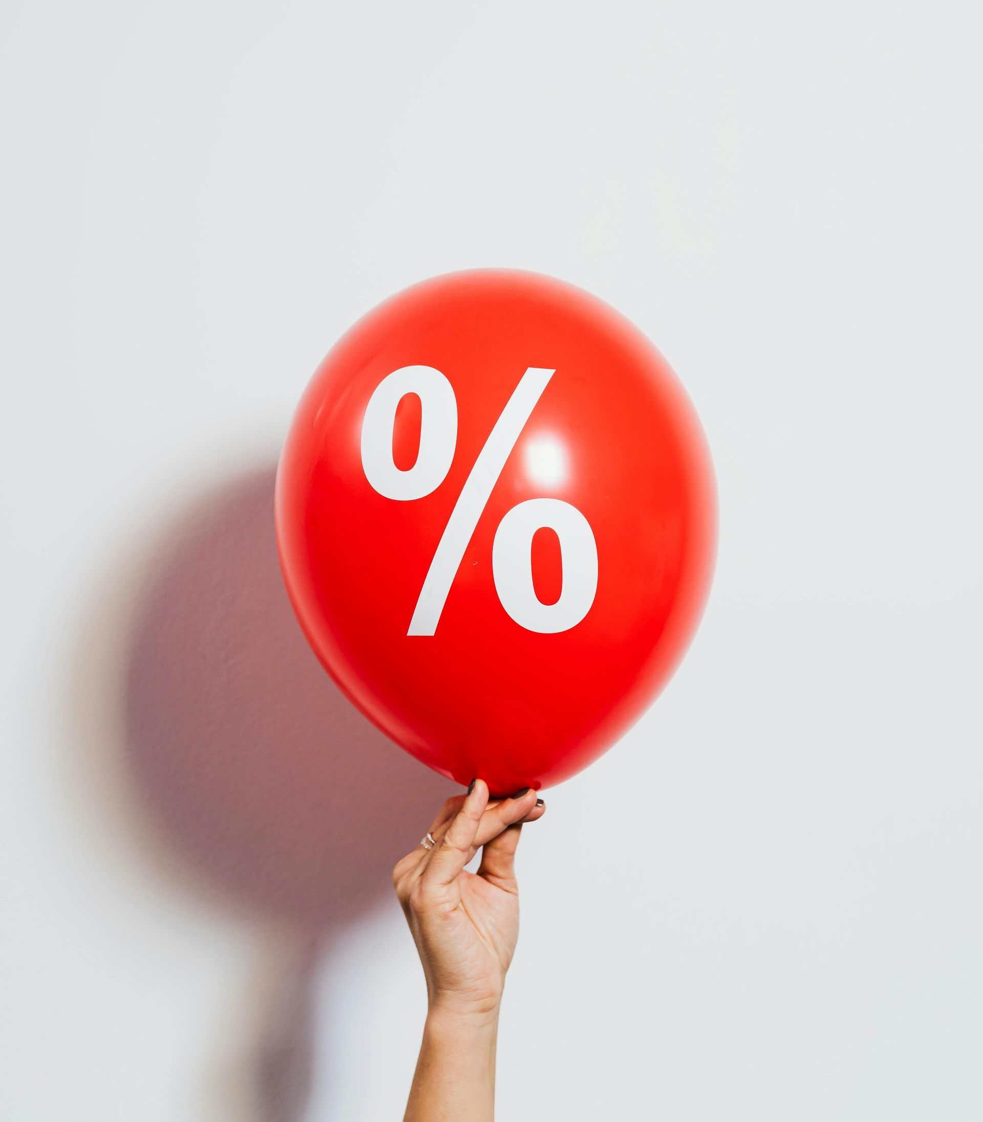 Red balloon with white percentage sign, held by a hand.