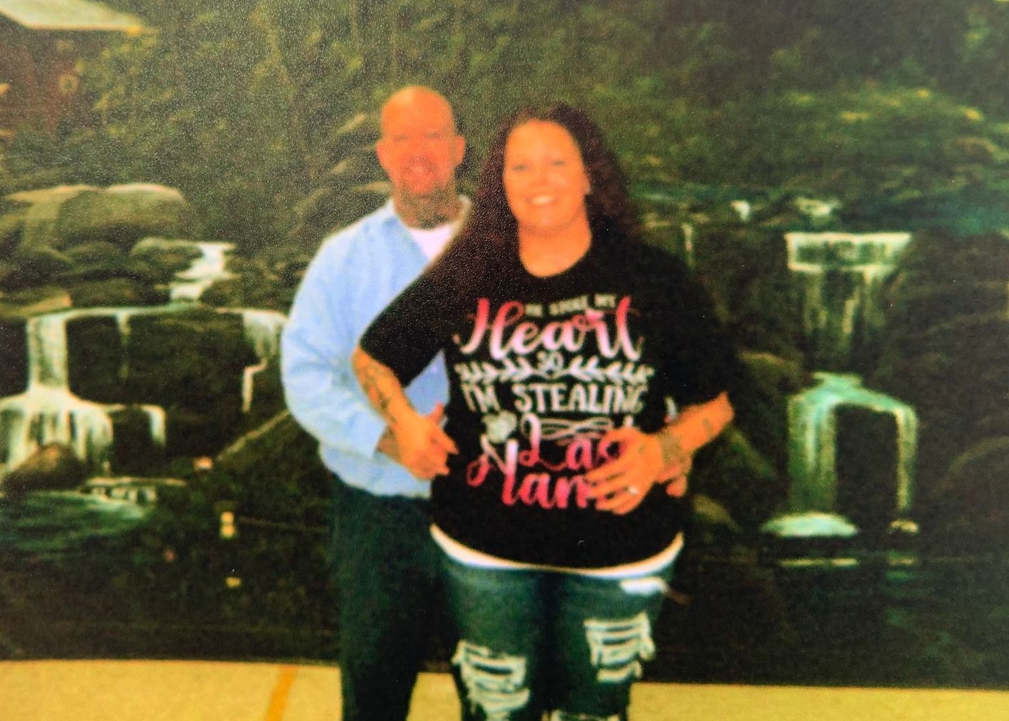 A man and a woman are posing for a picture and the woman is wearing a shirt that says heart on it