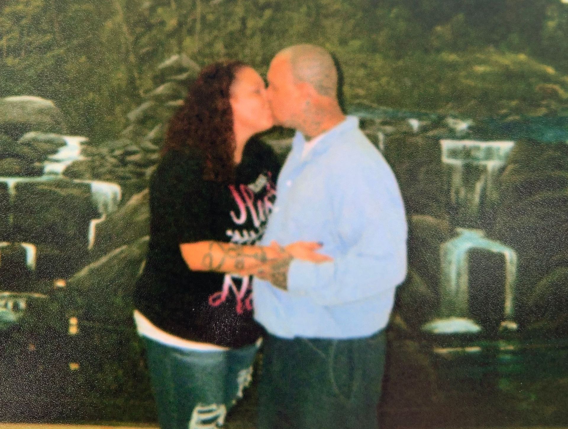 A man and a woman are kissing in front of a waterfall