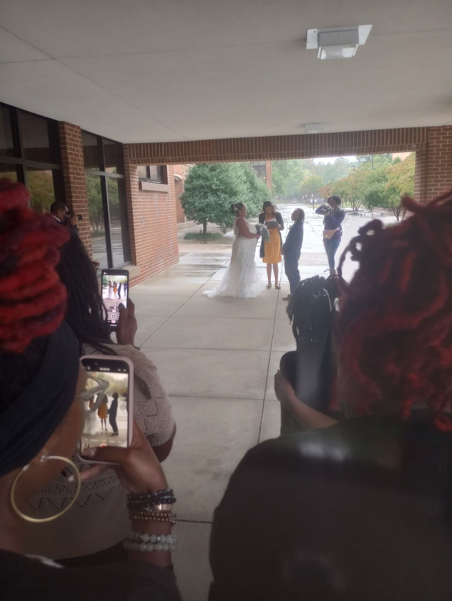 A group of people are taking pictures of a bride and groom