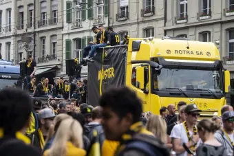 Un groupe de personnes se tient devant un camion jaune.