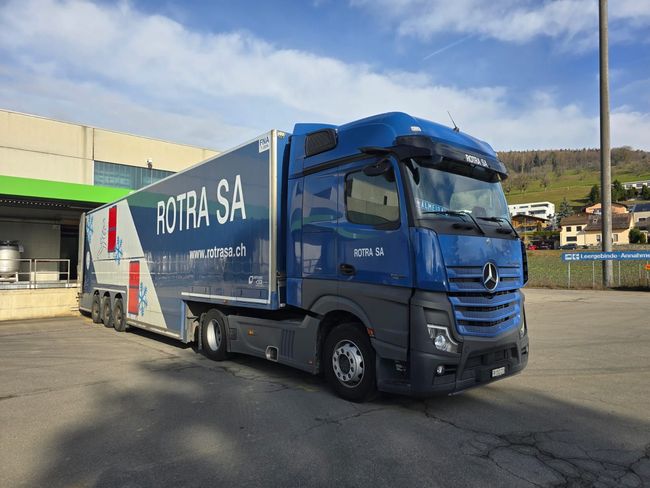 Un semi-remorque bleu est garé devant un entrepôt