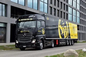 Un camion noir et jaune est garé devant un bâtiment.